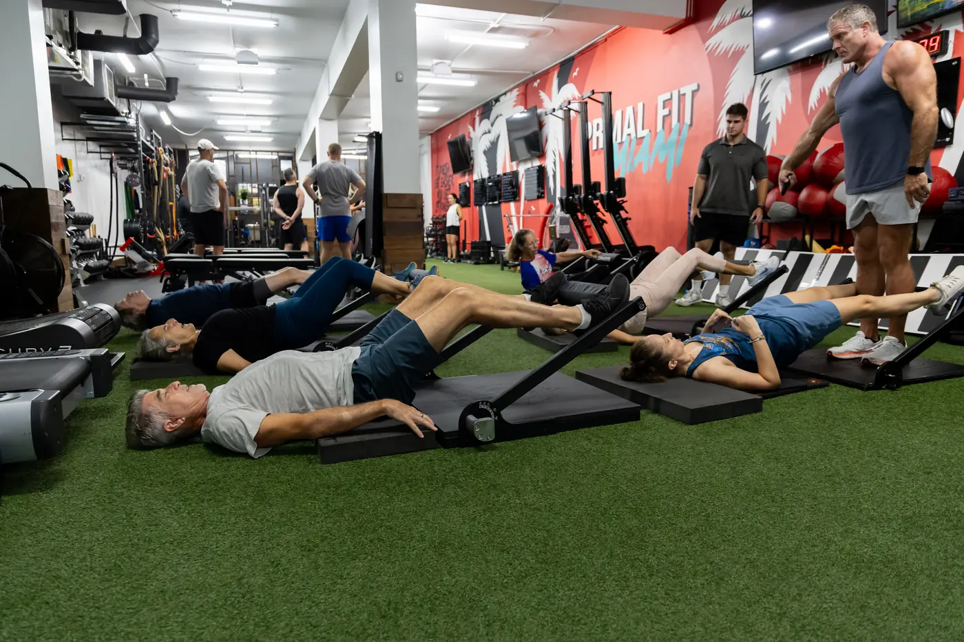 Coach guiding a small group through a coached isometric leg exercise at Primal Fit Miami