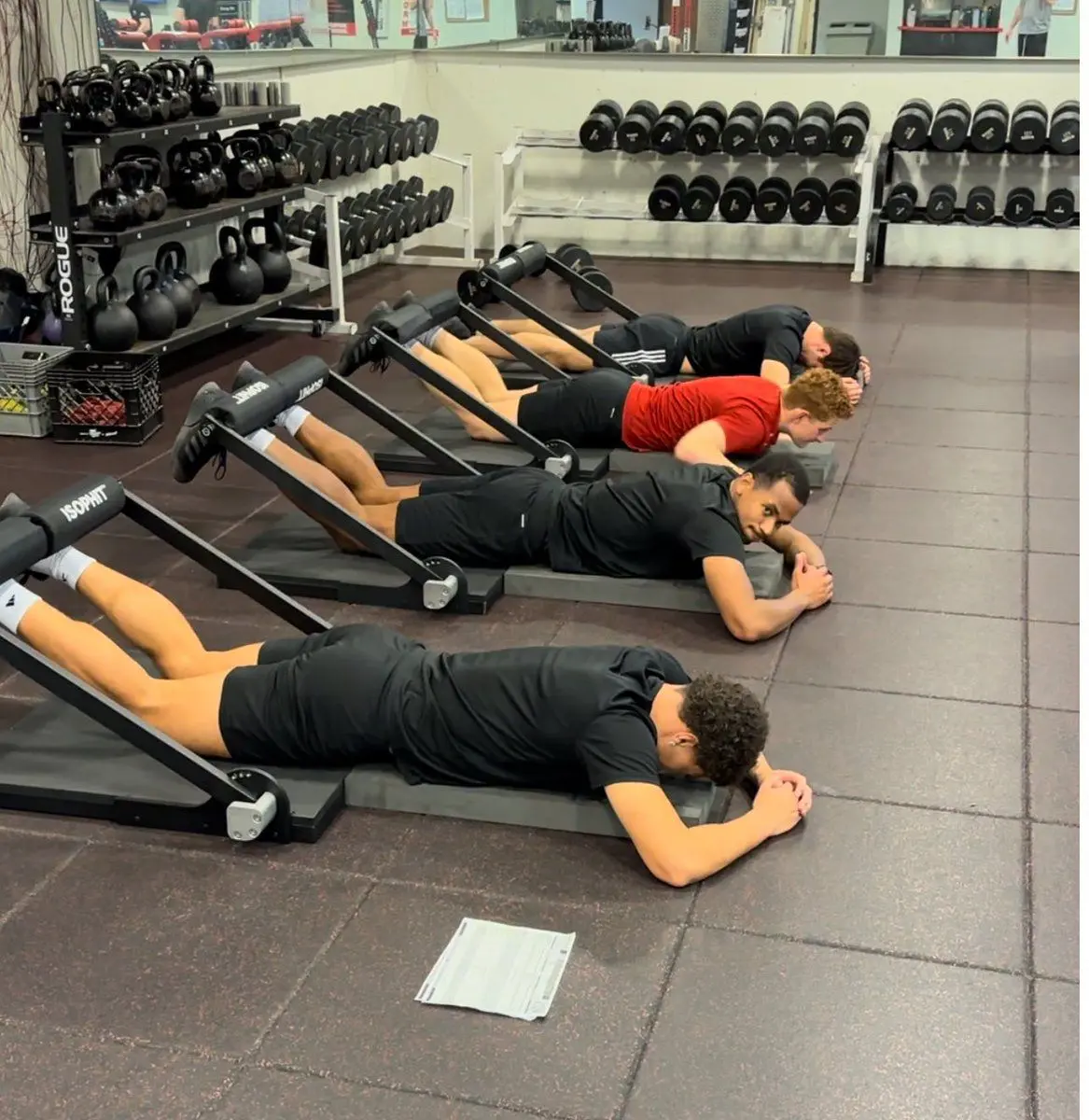 Young athletes training together in a row on ISOPHIT machines at Primal Fit Miami